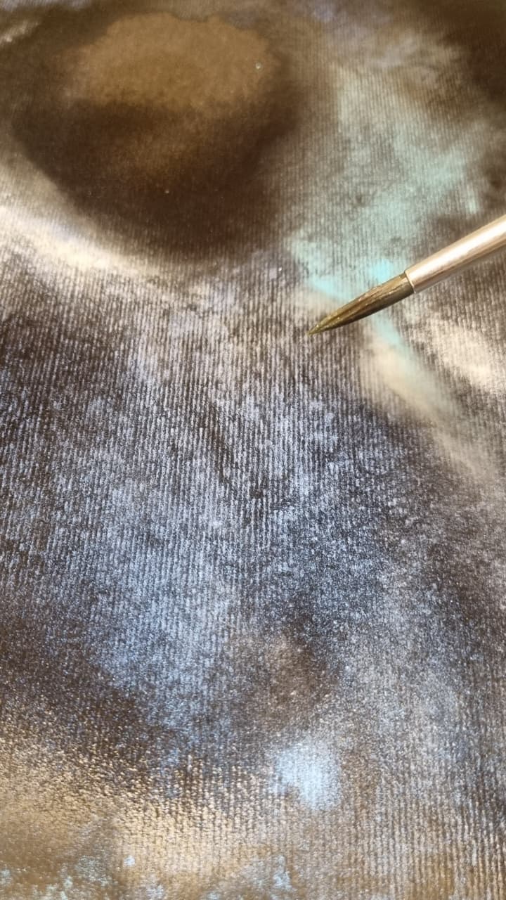 Pincel aplicando acuarela sobre fondo oscuro